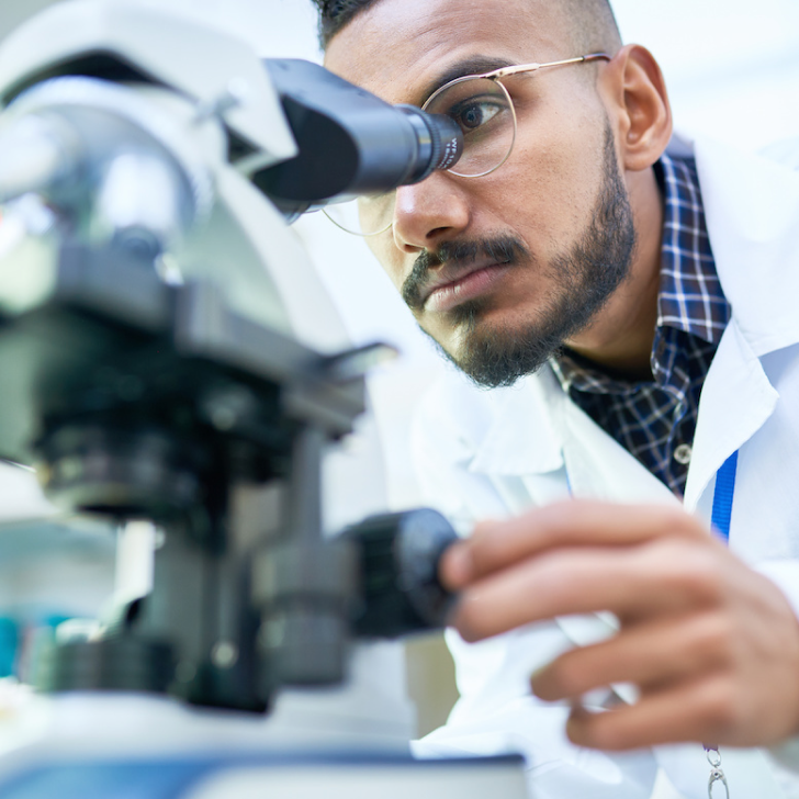 scientist looking through microscope